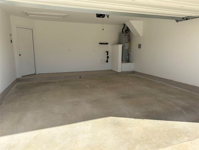 Garage featuring a garage door opener and electric water heater | Image 24
