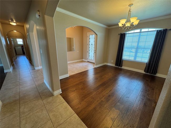 Empty room with a wealth of natural light, arched walkways, an inviting chandelier, and crown molding | Image 4