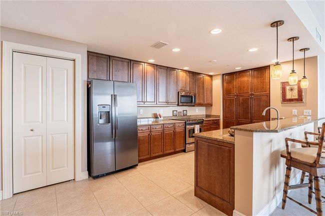 Kitchen with pendant lighting, appliances with stainless steel finishes, stone countertops, kitchen peninsula, and a kitchen breakfast bar | Image 18