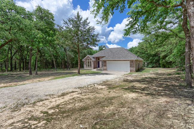 View of front of property featuring dirt driveway, an attached garage, brick siding, and a shingled roof | Image 28