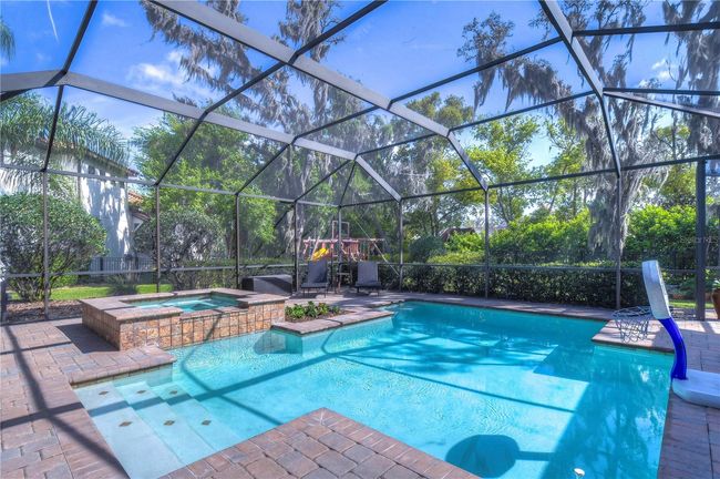 Dive into luxury with this exquisite screened-in pool and spa area, perfect for all-year entertainment against a backdrop of lush greenery. | Image 35