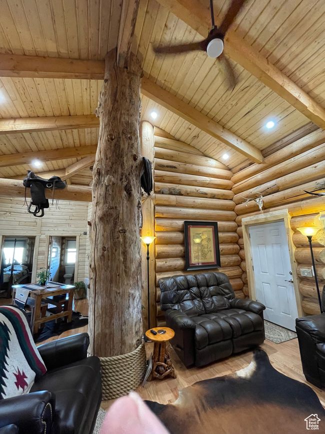 Living room featuring lofted ceiling with beams, wood finished floors, a ceiling fan, rustic walls, and wood ceiling | Image 100