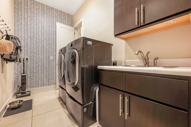 Laundry area with cabinet space, washing machine and dryer, and light tile patterned floors | Image 11