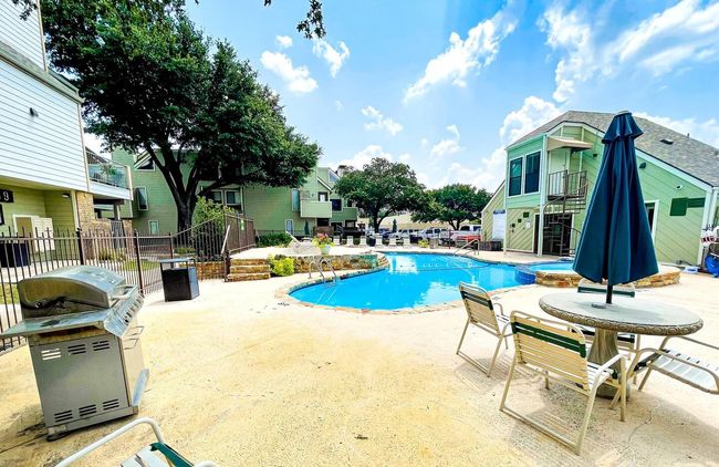 View of swimming pool featuring a patio, fence, a pool with connected hot tub, stairs, and grilling area | Image 16