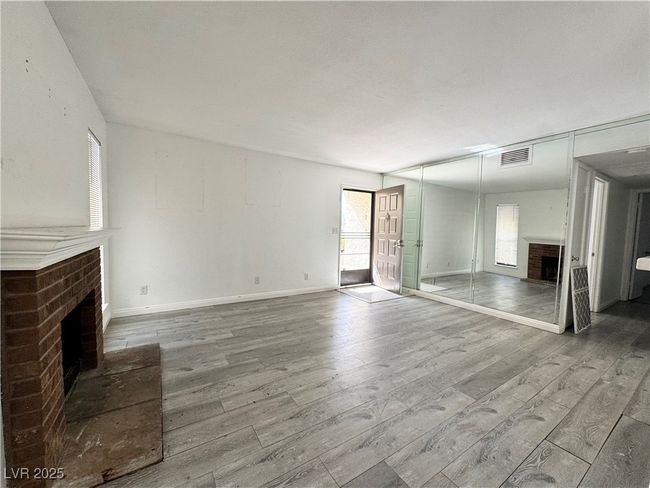 Unfurnished living room with a fireplace, wood finished floors, and baseboards | Image 11