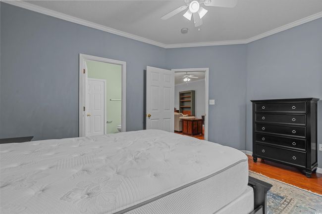 Bedroom with wood finished floors, ornamental molding, baseboards, a ceiling fan, and connected bathroom | Image 23