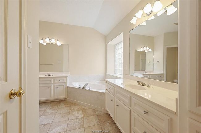 Bathroom with vaulted ceiling, a garden tub, two vanities, and toilet | Image 16