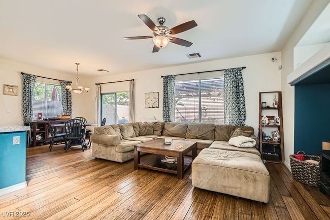 Living area with visible vents, ceiling fan with notable chandelier, and hardwood / wood-style flooring | Image 5