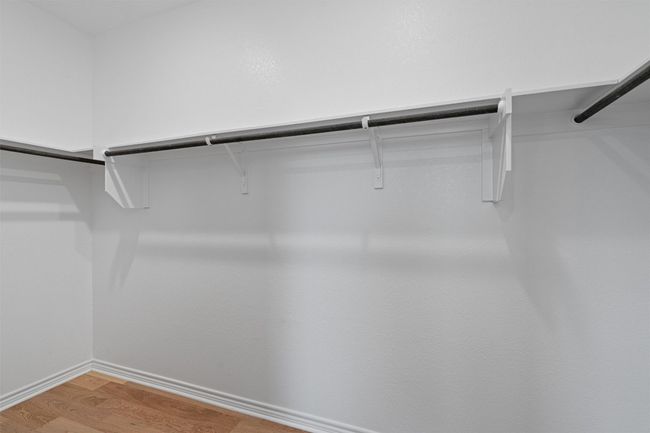 Primary bedroom walk in closet with light wood finished floors | Image 16