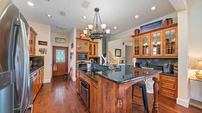 Kitchen featuring visible vents, stainless steel appliances, a kitchen island, a breakfast bar area, and brown cabinetry | Image 7