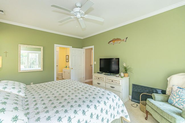 Bedroom featuring visible vents, ornamental molding, a ceiling fan, ensuite bath, and light colored carpet | Image 17