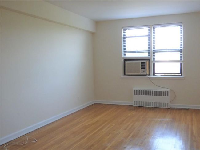 Living room with light wood-style floors, baseboards, and radiator | Image 12