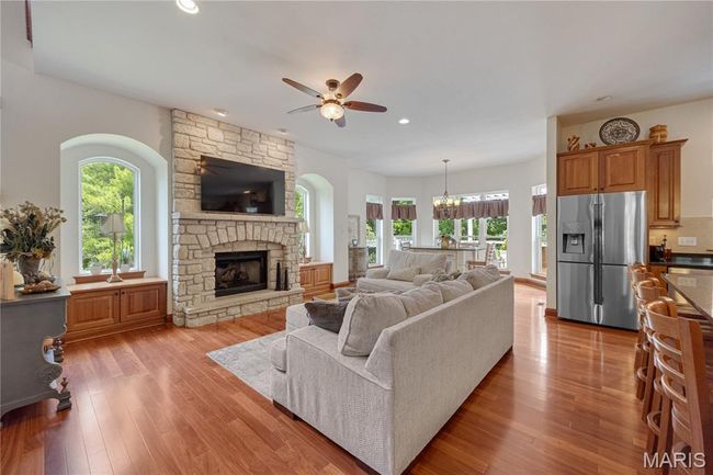 Living area featuring a ceiling fan, plenty of natural light, a stone fireplace, recessed lighting, and light wood-style flooring | Image 14
