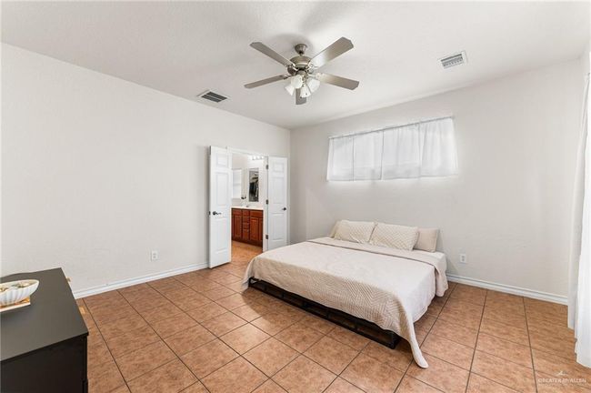 Bedroom featuring light tile patterned floors, ceiling fan, and ensuite bath | Image 13
