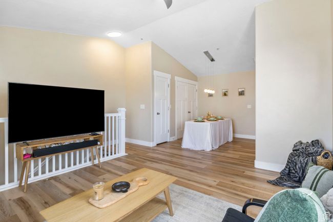 Living area with a ceiling fan, baseboards, light wood finished floors, and lofted ceiling | Image 9