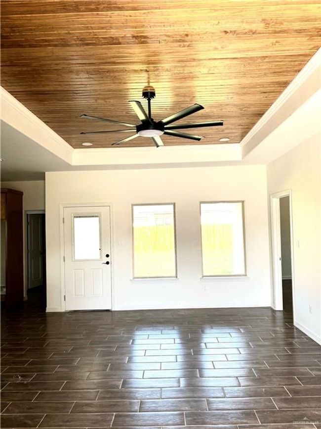 Empty room with wooden ceiling, a tray ceiling, and ceiling fan | Image 14
