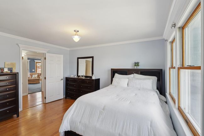 Bedroom featuring a baseboard heating unit, baseboards, crown molding, and wood finished floors | Image 23