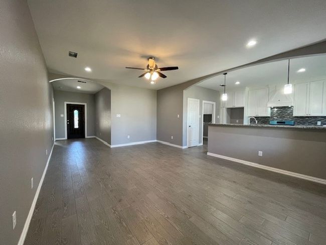 Living room facing front door with arched walkway, wood-style flooring, recessed lighting, a ceiling fan, and baseboards | Image 4