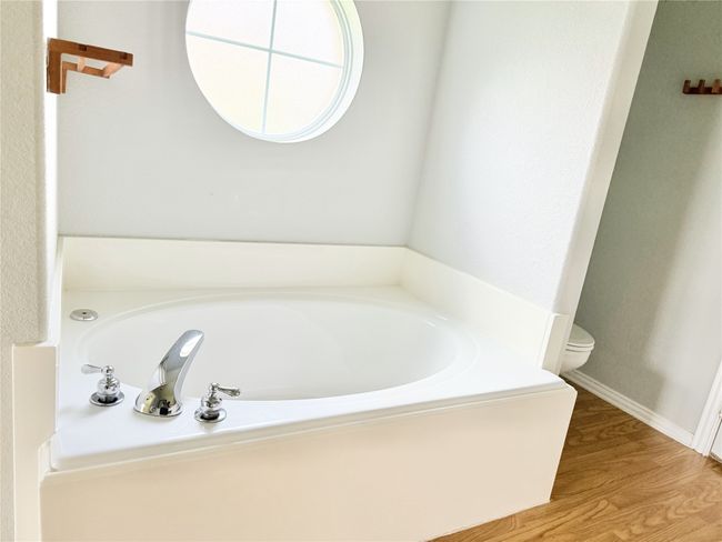 Bathroom with toilet, a bath, wood finished floors, and baseboards | Image 11