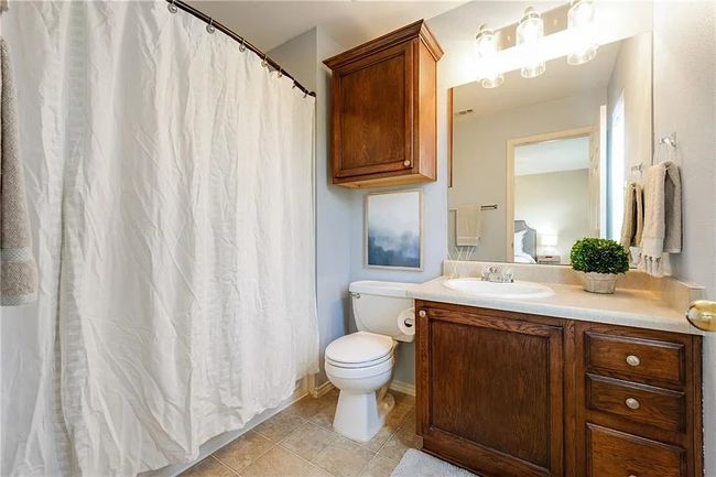 Full bathroom with toilet, vanity, tile patterned flooring, and a shower with shower curtain | Image 11