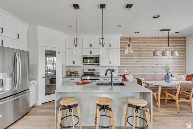 Kitchen featuring appliances with stainless steel finishes, light wood-type flooring, backsplash, a breakfast bar area, and recessed lighting | Image 26