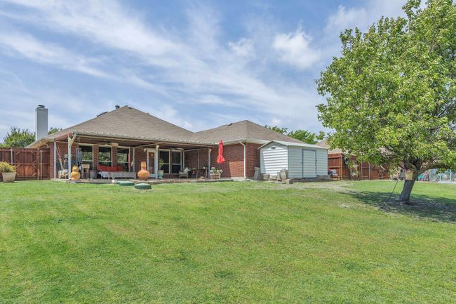 Back of house with brick siding, a patio area, a lawn, and a fenced backyard | Image 38