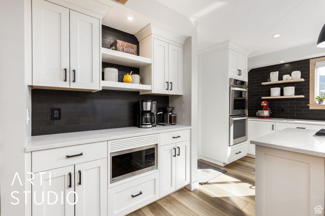 Kitchen with open shelves, appliances with stainless steel finishes, decorative backsplash, and white cabinets | Image 14