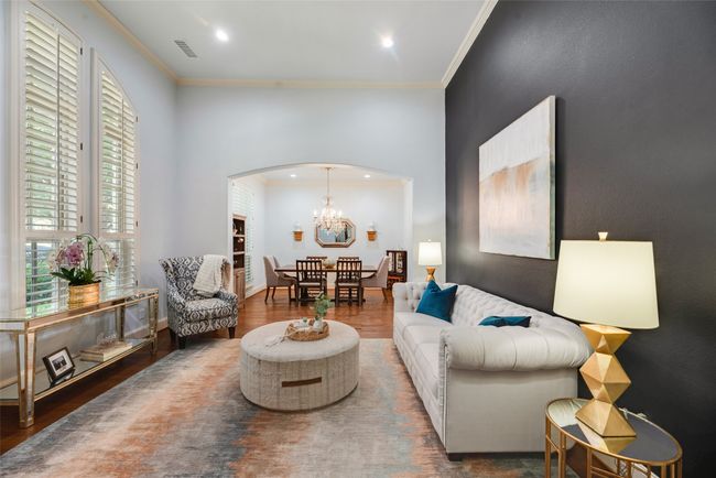 Living room with arched walkways, wood finished floors, crown molding, a chandelier, and recessed lighting | Image 25