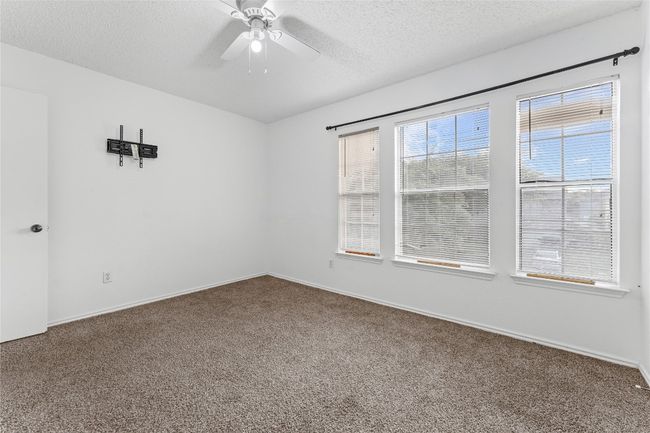 Carpeted spare room featuring ceiling fan, a textured ceiling, and baseboards | Image 30