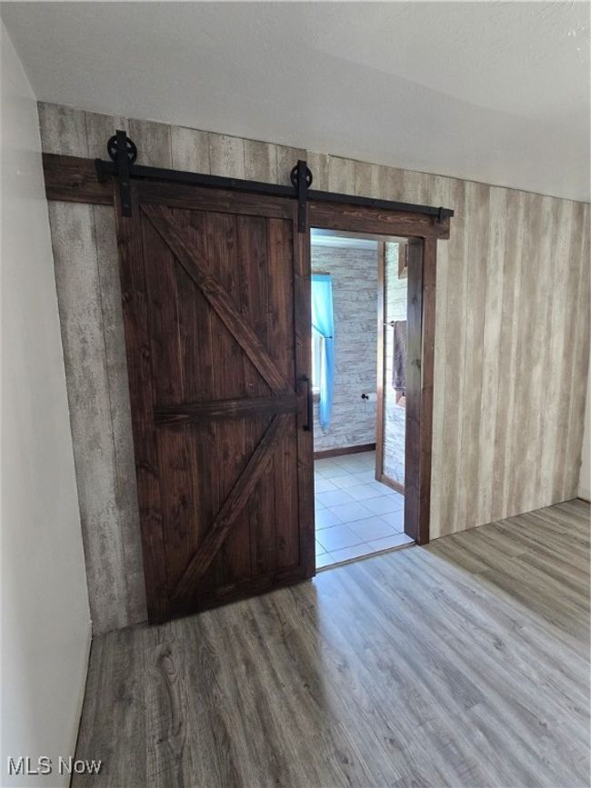 Spare room with wood finished floors and a barn door | Image 17