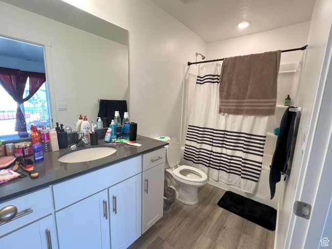 Bathroom featuring wood finished floors, vanity, toilet, and shower / bath combo with shower curtain | Image 4