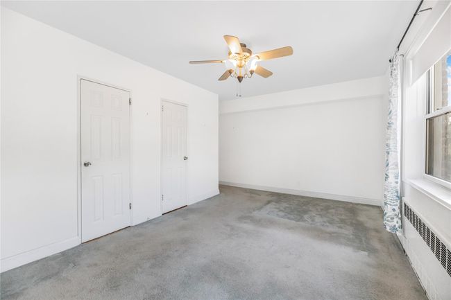 Unfurnished bedroom with radiator, carpet flooring, and ceiling fan | Image 16