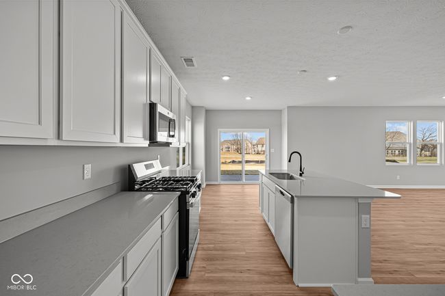 kitchen with light wood-style flooring, baseboards, a kitchen island with sink, appliances with stainless steel finishes, and a sink | Image 8