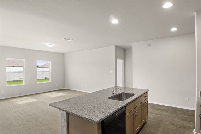 Kitchen with light stone counters, dark wood-style floors, black dishwasher, visible vents, and a sink | Image 7