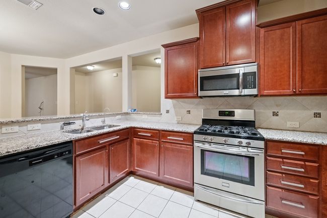 Kitchen with stainless steel appliances, light stone counters, tasteful backsplash, light tile patterned floors, and recessed lighting | Image 4