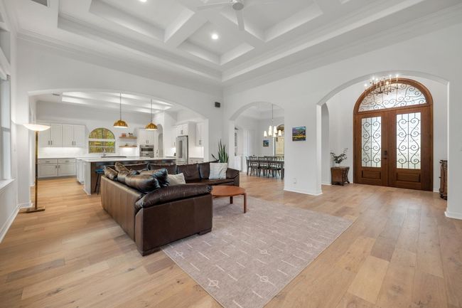 Living area featuring a high ceiling, a chandelier, arched walkways, coffered ceiling, and beamed ceiling | Image 6