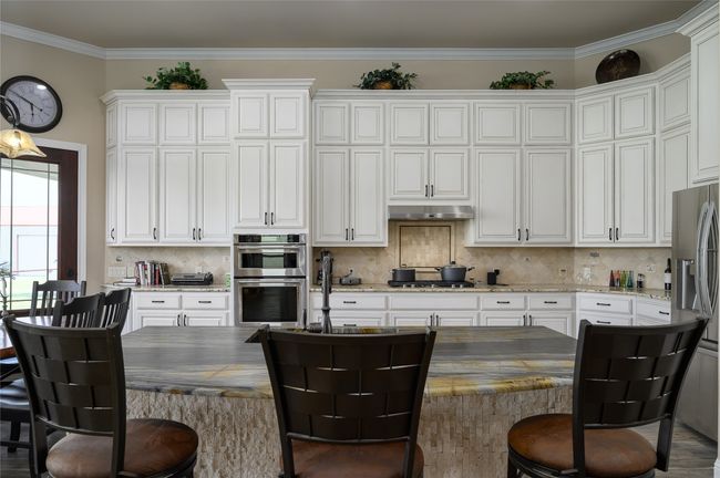 Kitchen featuring white cabinets, under cabinet range hood, and appliances with stainless steel finishes. Note the extensive cabinets. | Image 12