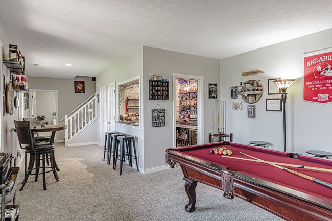 rec room featuring baseboards, carpet, a textured ceiling, and a bar | Image 40