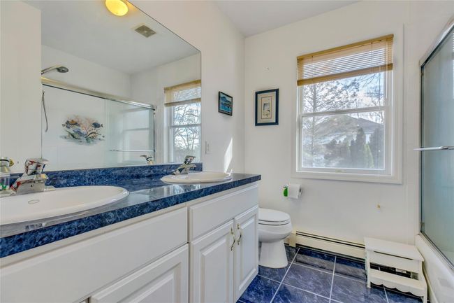 Full bathroom featuring baseboard heating, vanity, toilet, and combined bath / shower with glass door | Image 18