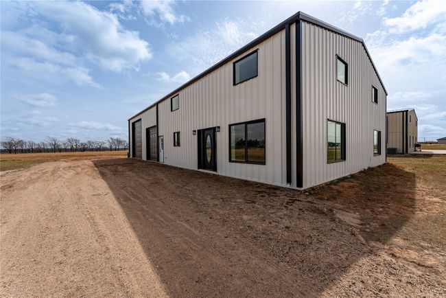 View of property exterior featuring a garage, dirt driveway, and an outdoor structure | Image 23