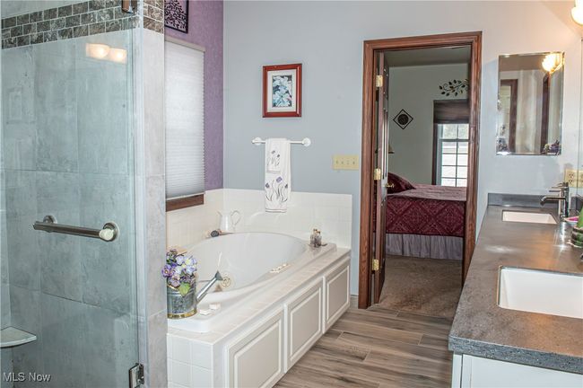 Bathroom featuring a bath, double vanity, a sink, and a shower stall | Image 11