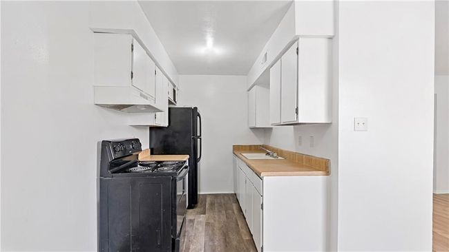 Kitchen featuring white cabinetry, wood-type flooring, sink, and electric range | Image 23