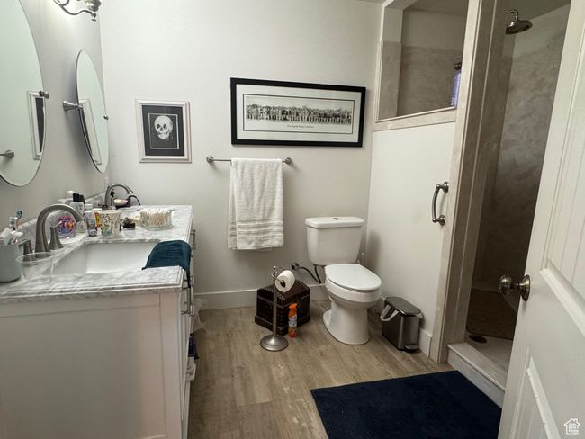 Full bathroom with a tile shower, toilet, wood finished floors, and vanity | Image 11