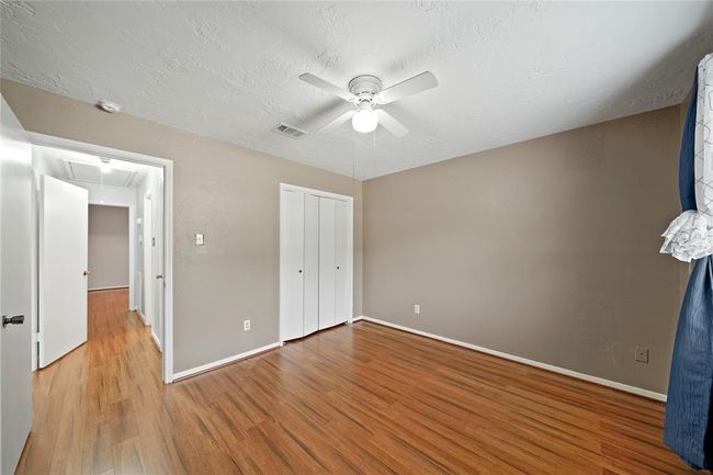 The third bedroom has a closet with white doors and an adjoining hallway to the other bedroom and bathroom. | Image 24