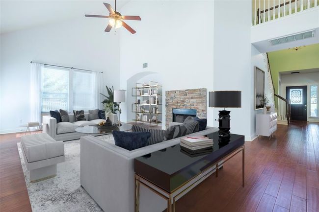 Virtually staged Living room with a high ceiling, a ceiling fan, dark wood finished floors, stairway, and baseboards | Image 11