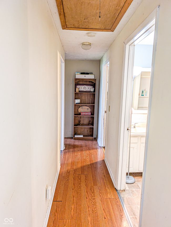hall featuring light wood finished floors, a sink, and baseboards | Image 13