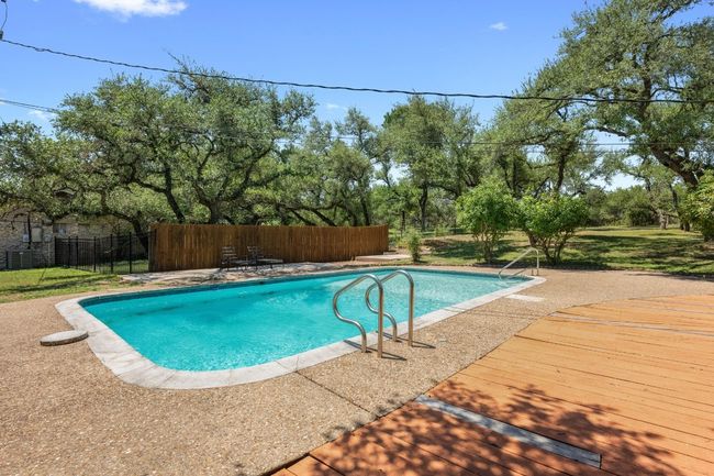 View of pool with a wooden deck, and view of scattered trees | Image 24