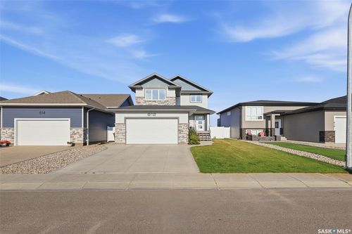 Multi-level residence featuring a prominent double garage, stone and siding exterior, and a concrete driveway | Card Image