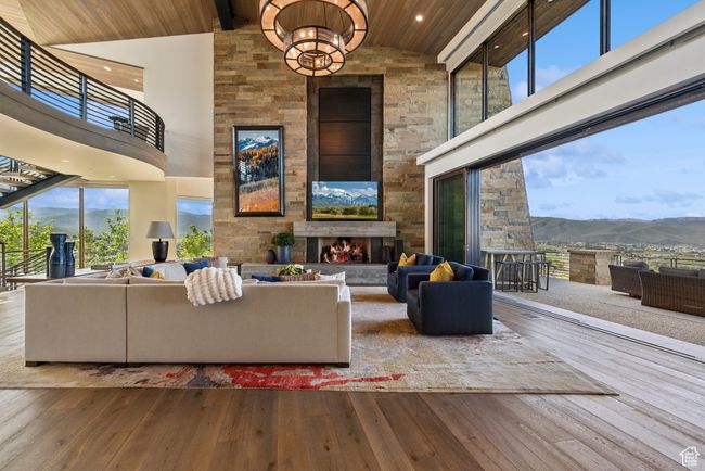 Living area featuring a mountain view, an outdoor stone fireplace, wood ceiling with exposed beams, high vaulted ceiling, and hardwood / wood-style floors | Image 9