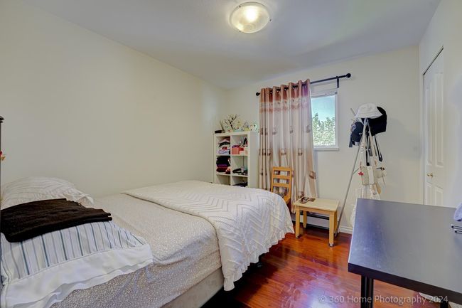 Bedroom with a baseboard heating unit and wood finished floors | Image 10